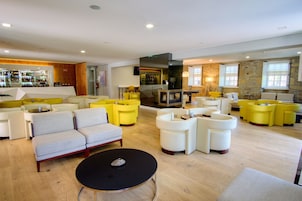 Uma área de estar moderna com sofás, poltronas e um bar.