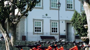 A building with a sign reading "Fontes Velha Hotel" and a row of bicycles parked in front.