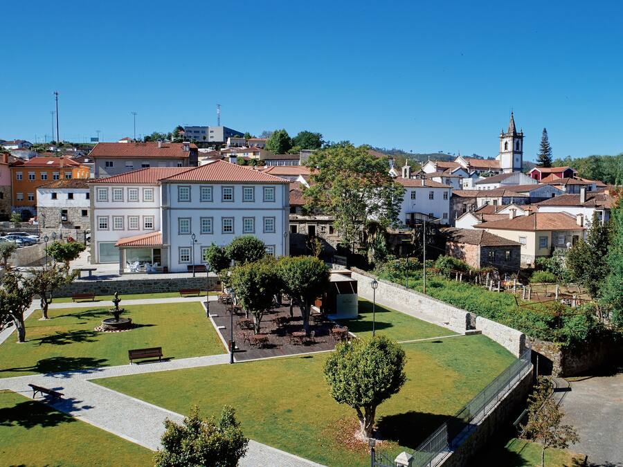 Un pueblo histórico con una plaza central, edificios tradicionales y una imponente torre de iglesia.