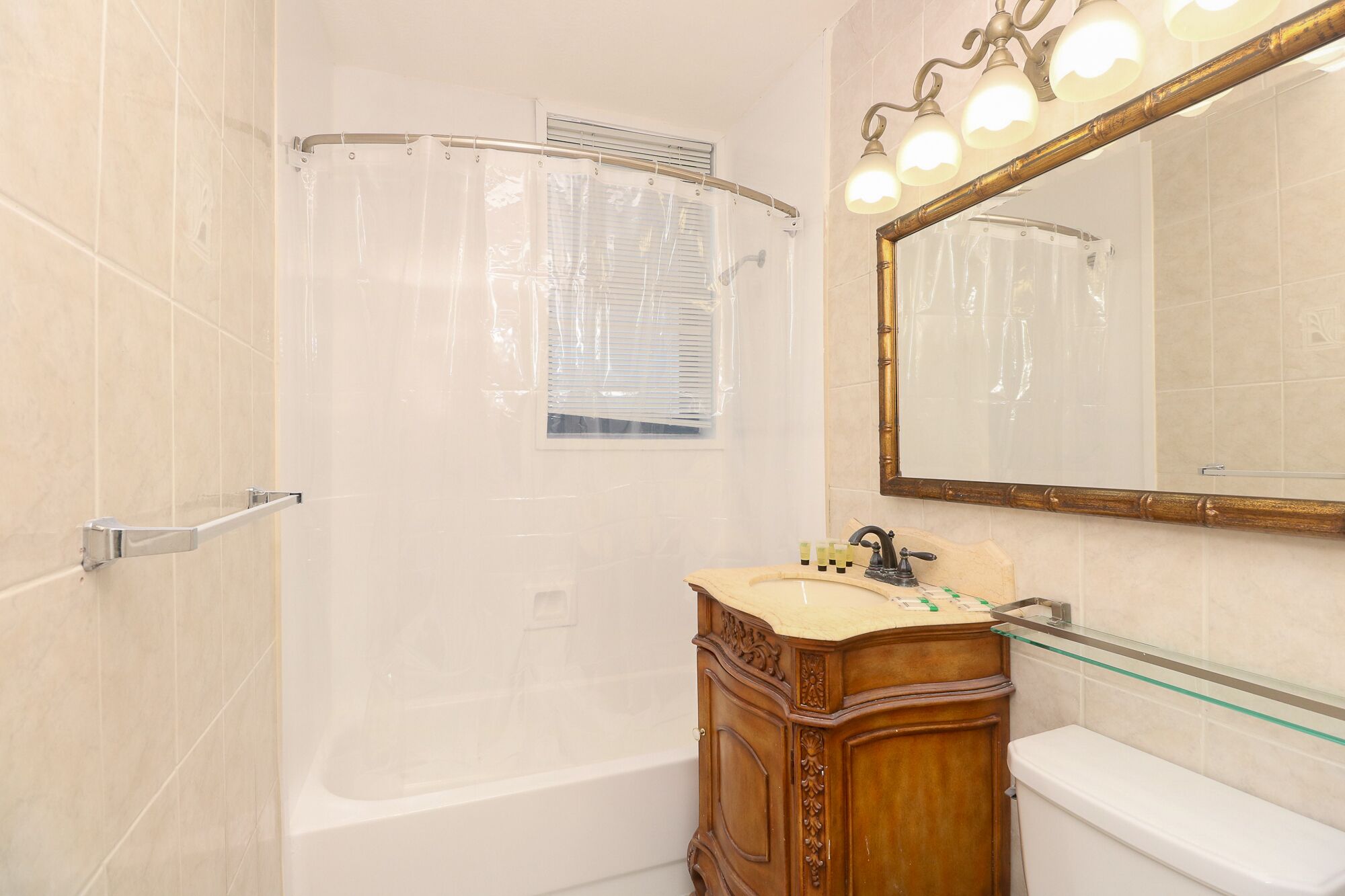 A bathroom with a bathtub, a vanity with a mirror, and a shower curtain.
