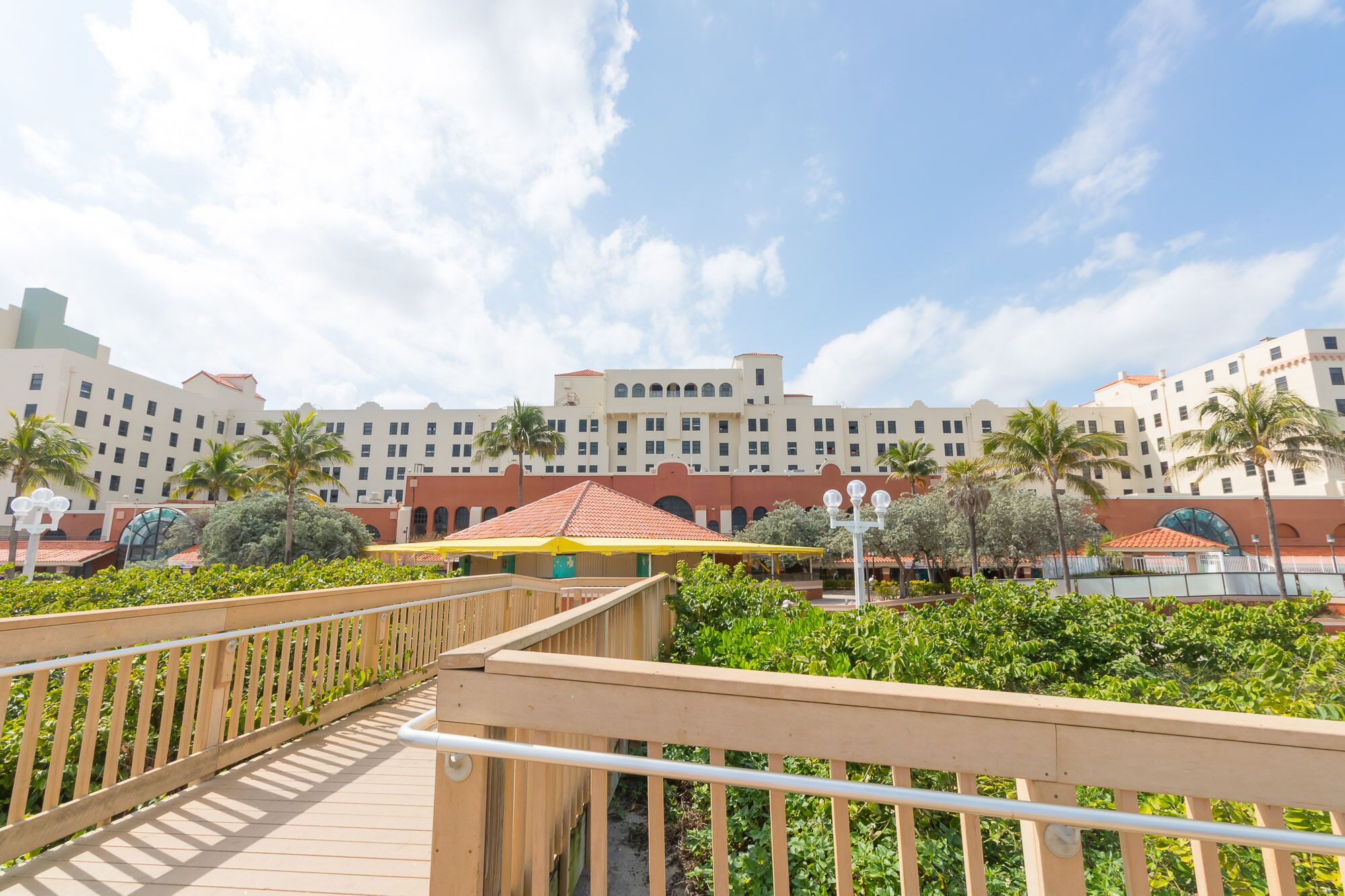 A hotel with multiple buildings, a wooden deck, and palm trees.