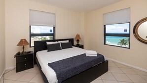 A bedroom with a bed, two bedside tables, a lamp, a window with a view, and a mirror on the wall. - 661 Partial Ocean View Hollywood Beach (Hollywood)
