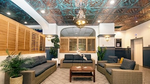 A lobby with wicker furniture, a wooden bench, and a ceiling with a geometric pattern. - 661 Partial Ocean View Hollywood Beach (Hollywood)