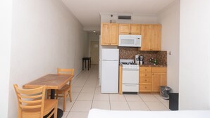 A compact kitchen with wooden cabinets, a microwave, a stove, and a refrigerator. - 519 City View Hollywood Beach (Hollywood)