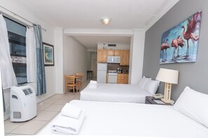 A hotel room with two beds, a kitchenette, a dining area, and a painting of flamingos. - 519 City View Hollywood Beach (Hollywood)