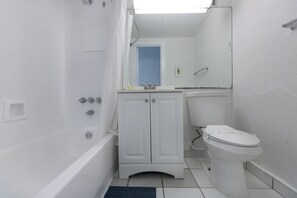 A small, white bathroom with a bathtub, a toilet, and a sink. - 519 City View Hollywood Beach (Hollywood)