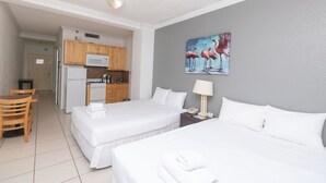 A hotel room with two beds, a kitchenette, and a painting of flamingos. - 519 City View Hollywood Beach (Hollywood)