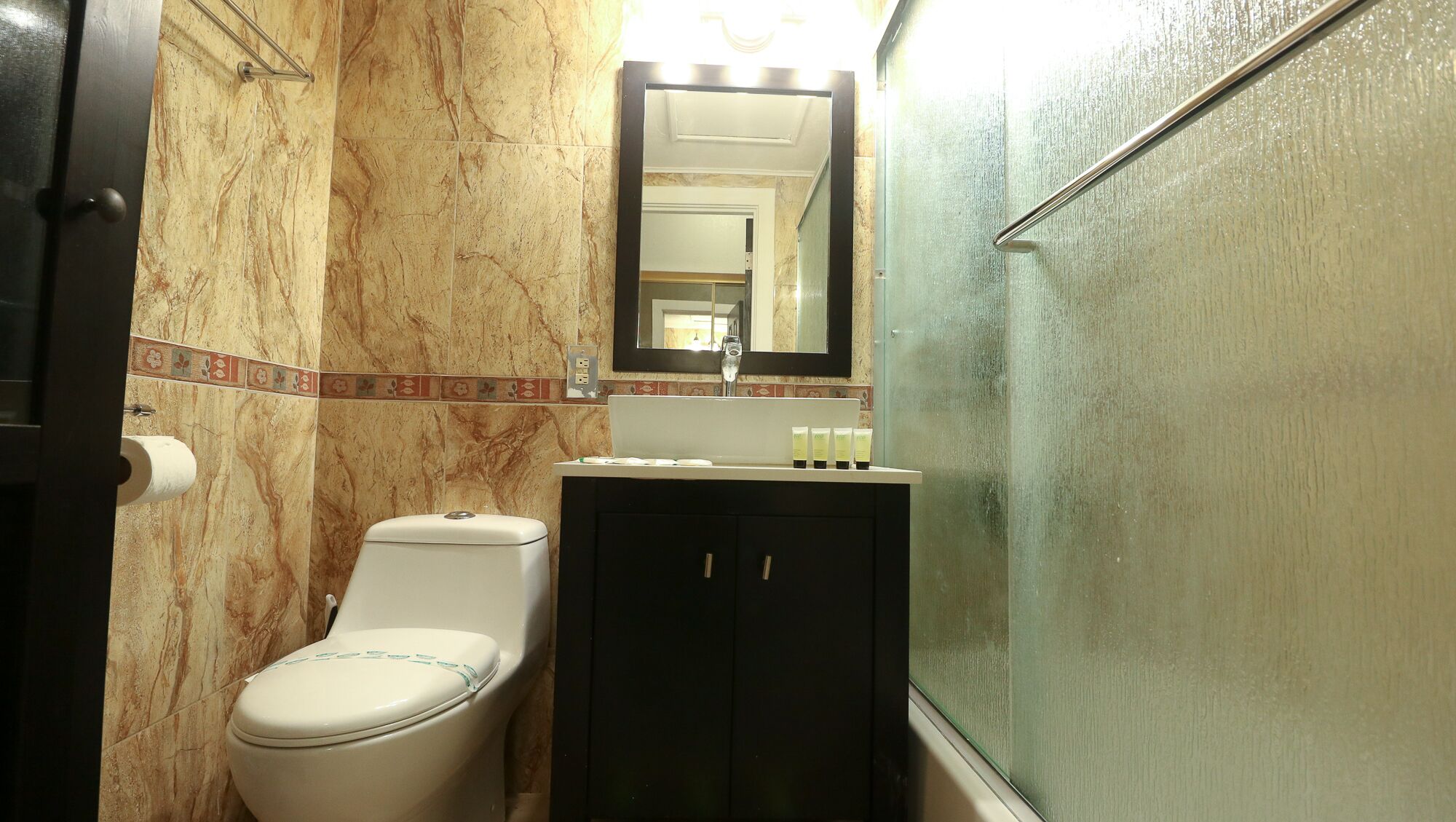 A bathroom with a toilet, a sink with a mirror above it, and a shower area.