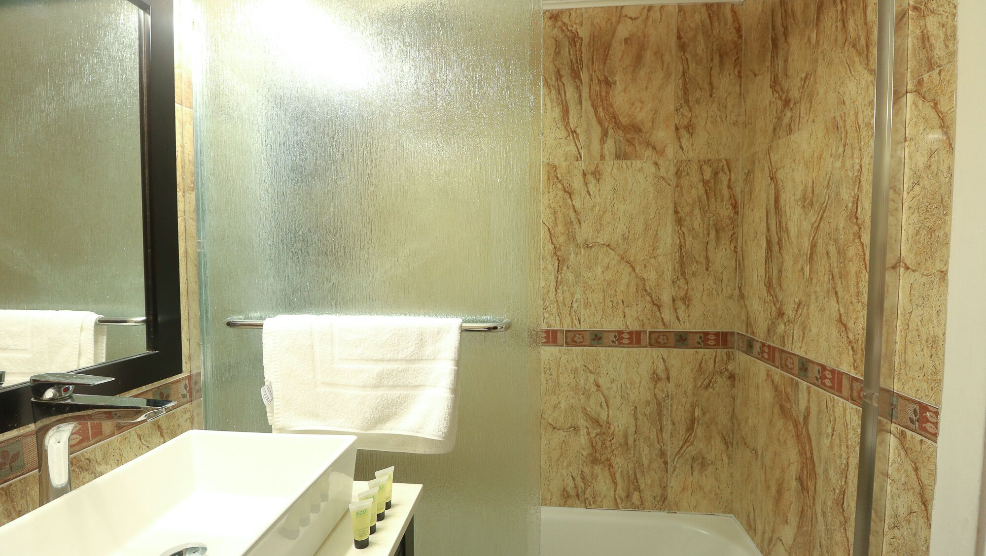 A bathroom with a white sink, a mirror, a towel rack, and a shower area with a glass door.
