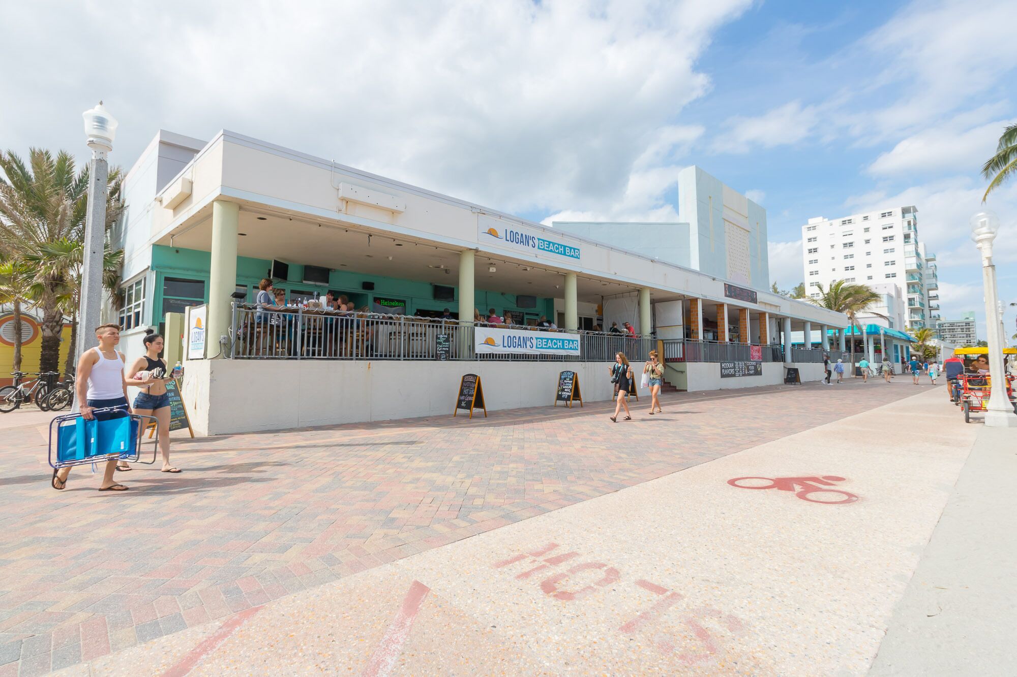 Un bar de playa con mesas al aire libre y un carril bici.