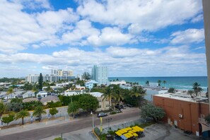 A coastal cityscape with a view of the ocean, buildings, and a parking area with yellow umbrellas. - 679 City View Hollywood Beach (Hollywood)