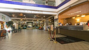 Een hotel lobby met een receptiebalie, een zithoek en een koffiebar.