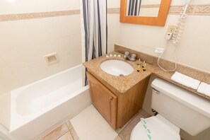 A bathroom with a bathtub, a sink with toiletries, a toilet, and a telephone. - 716 Partial Ocean View (Hollywood)