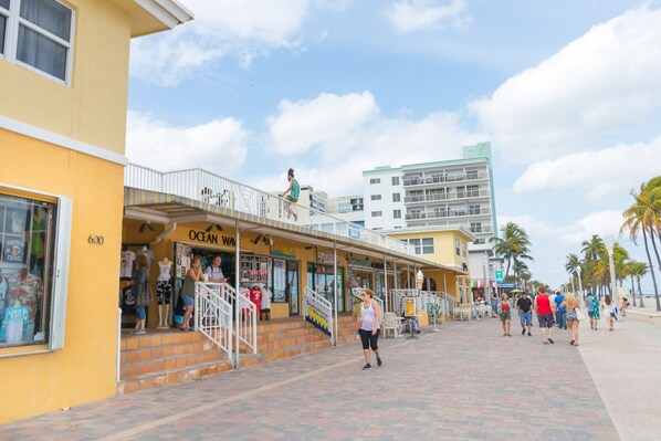 A coastal street with shops and a building with a balcony.