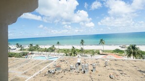 Vista de una playa con zona de piscina y palmeras.