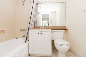 A bathroom with a bathtub, a toilet, and a vanity with a mirror.