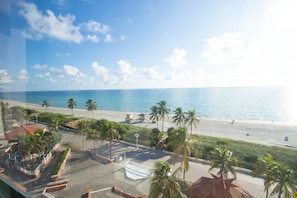 A beach view with palm trees, a lifeguard tower, and a clear sky.