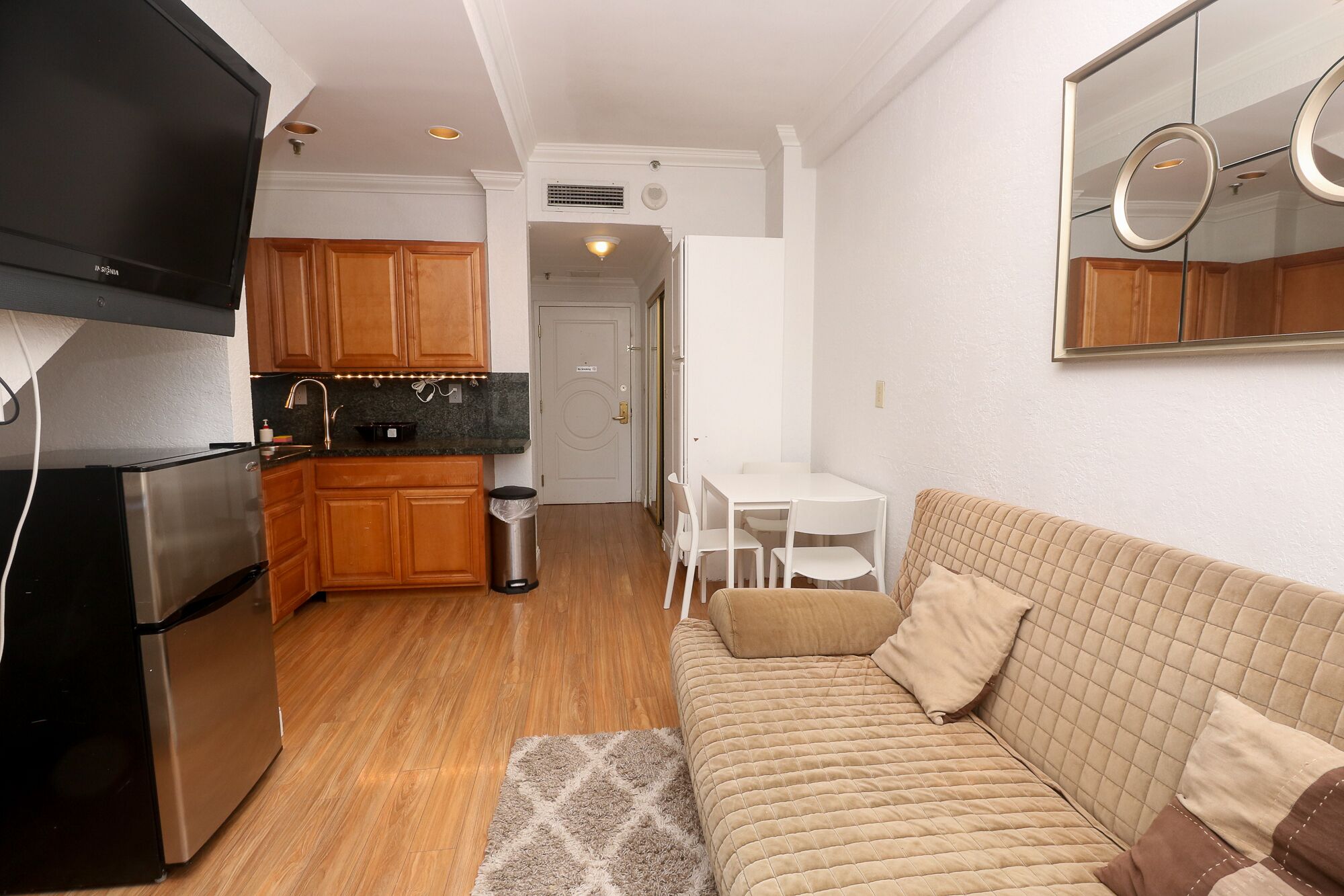A compact living space with a kitchenette, a sofa, and a dining area.