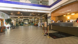 Een hotel lobby met een receptiebalie, een zithoek en een koffiebar.