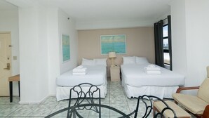 Habitació d'hotel amb dos llits, un escriptori, una cadira i vista a la ciutat.