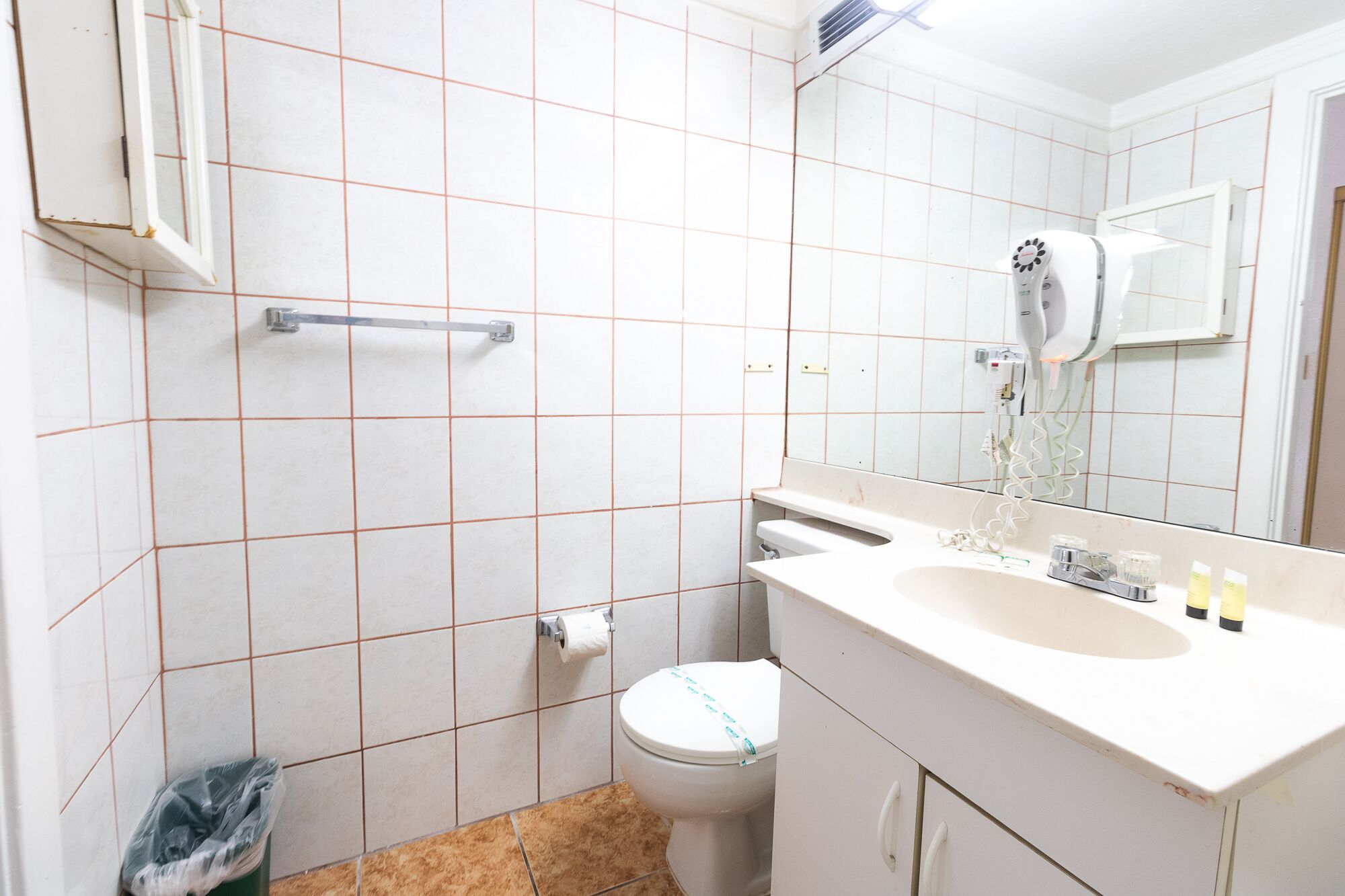 A bathroom with a toilet, sink, mirror, and towel rack.
