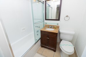 A bathroom with a glass shower enclosure, a sink with a granite countertop, a dark wooden cabinet, and a white toilet. - 707 Partial Ocean Hollywood Beach (Hollywood)