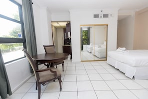 A hotel room with a bed, a dining table with chairs, a mirror, and a view of the outdoors. - 217 Hollywood Beach Resort (Hollywood)