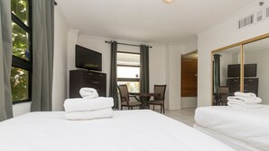 Ett hotellrum med två sängar, ett skrivbord, en stol, en tv och en stor spegel.