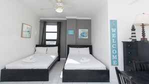 A room with two beds, a ceiling fan, a window with curtains, and a 'WELCOME' sign. - 584 Ocean View Studio Hollywood Beach (Hollywood)