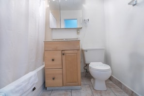 A small, clean bathroom with a wooden vanity, a toilet, and a mirror above the vanity. - 760 Ocean View Hollywood Beach (Hollywood)