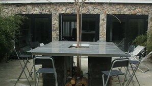 An outdoor dining area with a stone wall, a large table, and chairs. - Character house downtown, quiet street, near castle, harbor (Noirmoutier-En-L'île)