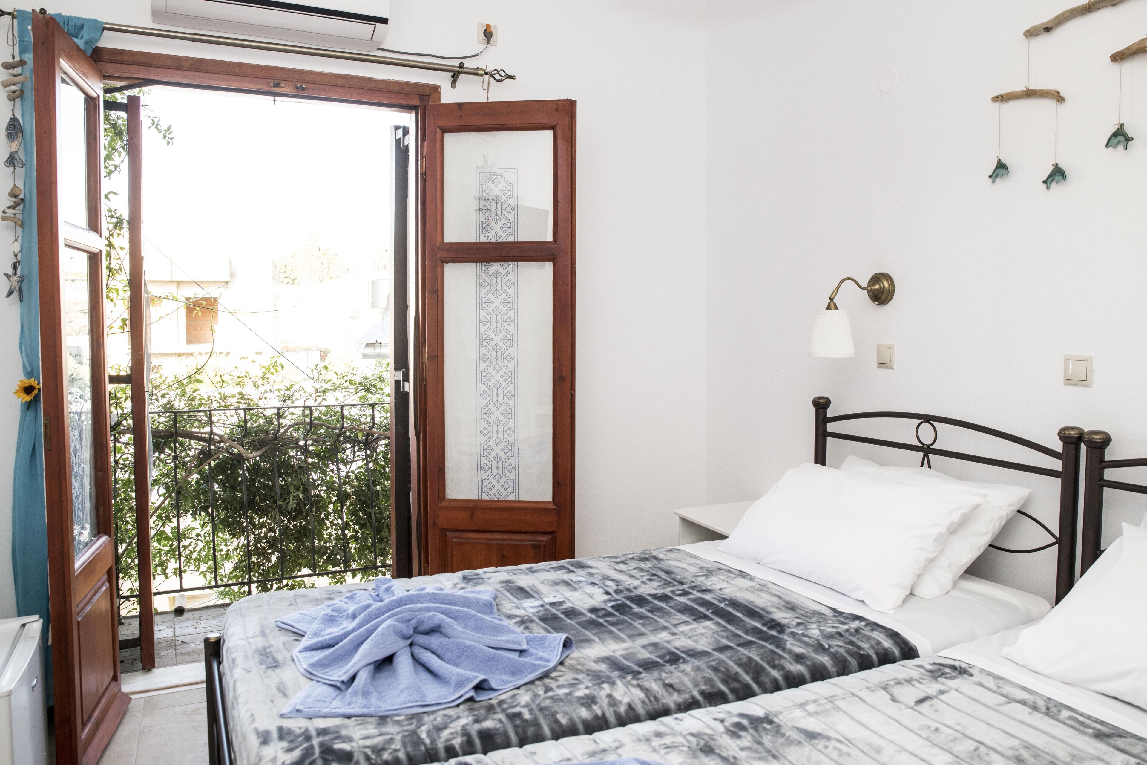 Un dormitorio con cama, ventana con vista a zonas verdes, lámpara de pared y puerta con panel decorativo.