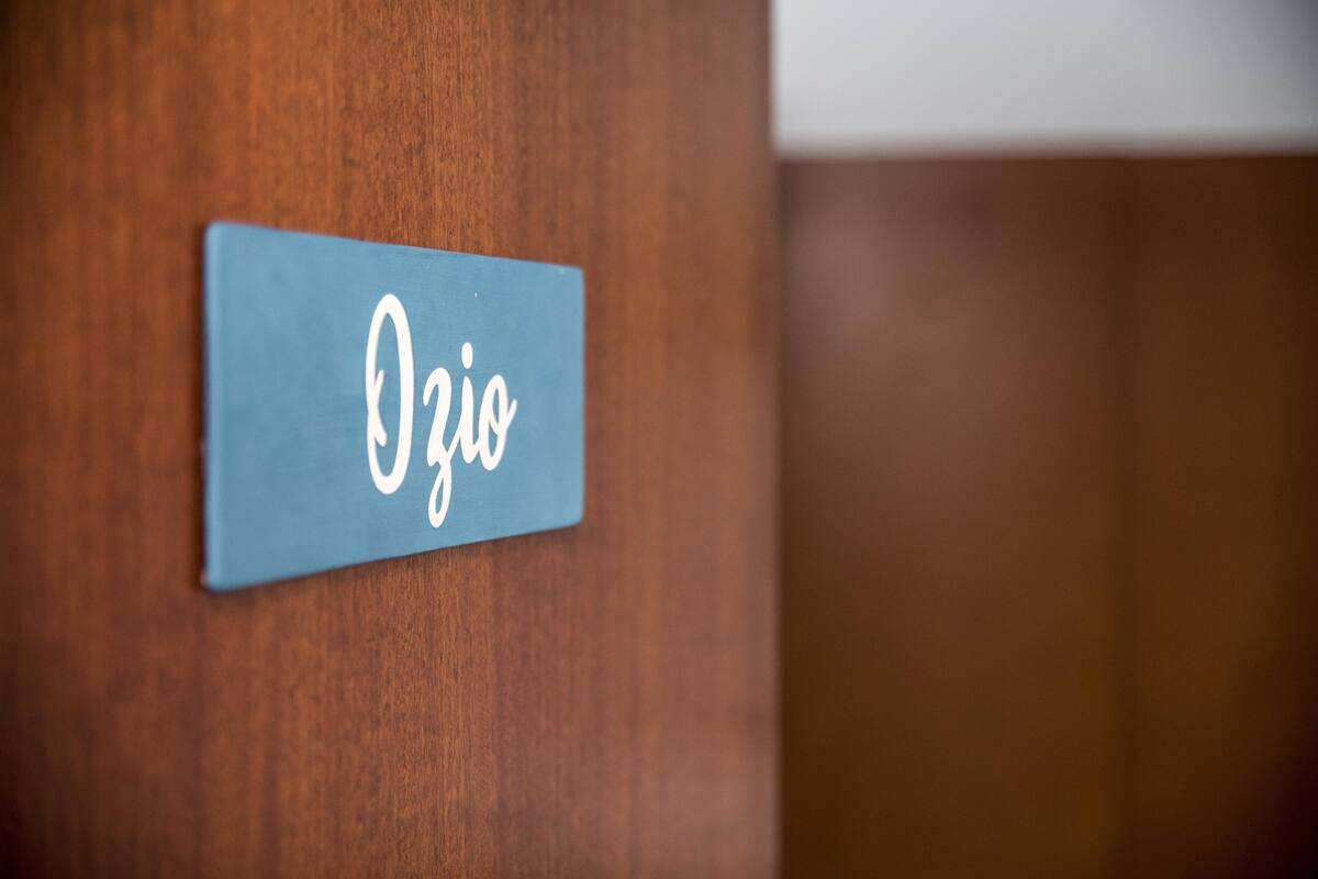 Une porte en bois avec une plaque nominative bleue sur laquelle on peut lire « Ozio ».