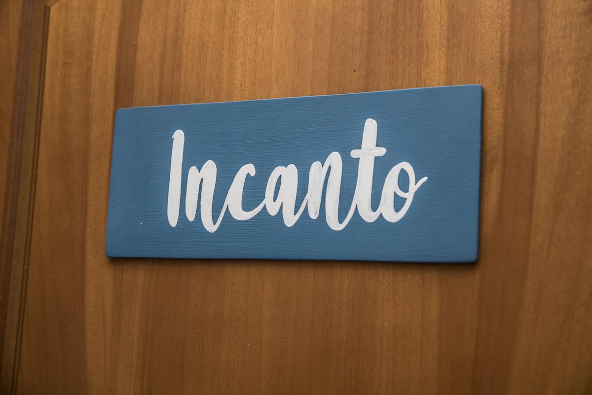 Un panneau bleu portant le mot « Incanto » sur une surface en bois.
