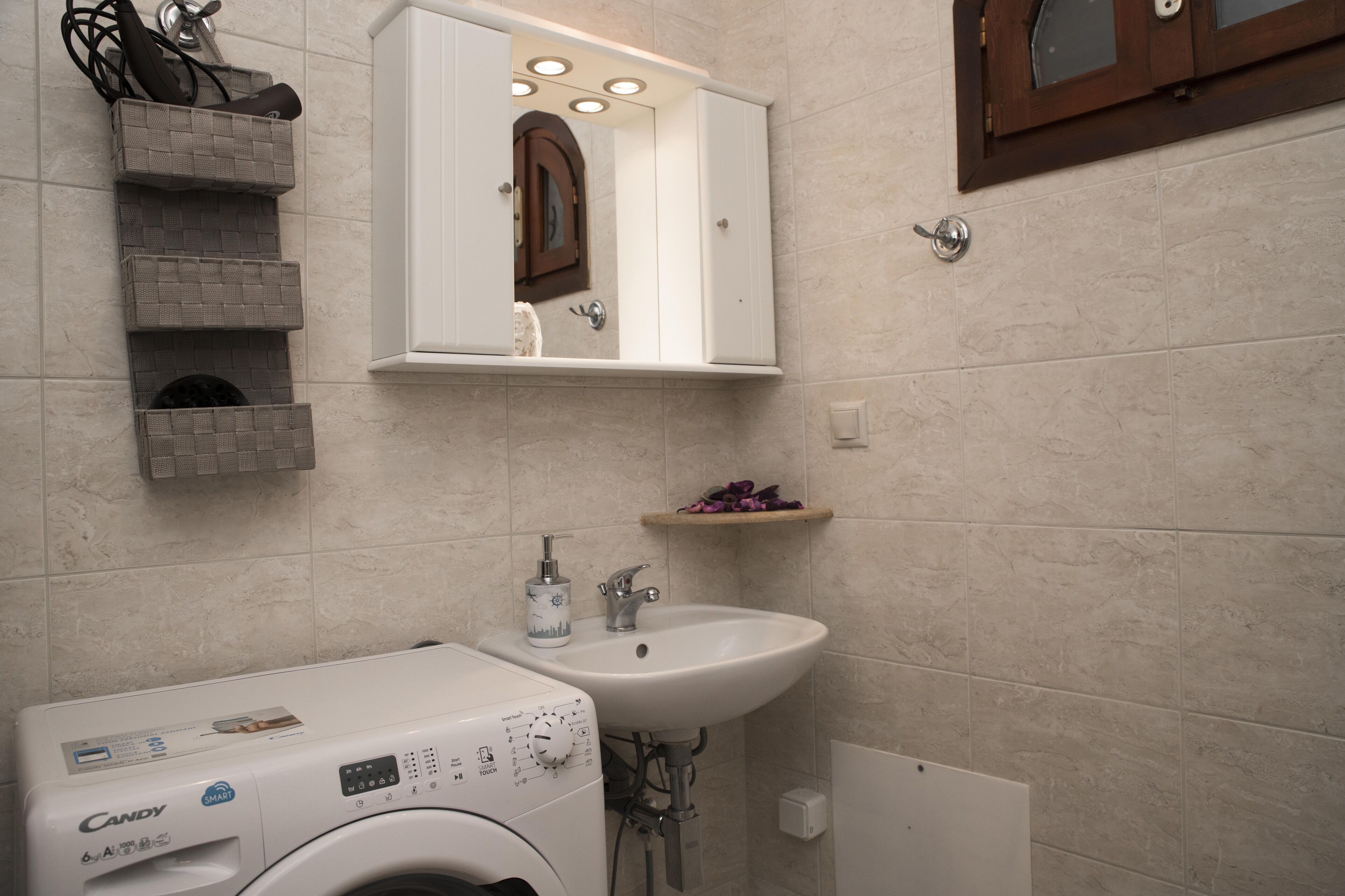 Ein modernes Badezimmer mit Waschmaschine, Waschbecken und einem Spiegel über dem Spiegelschrank.