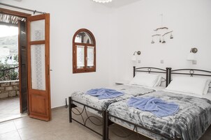 Ένα υπνοδωμάτιο με δύο κρεβάτια, μια ξύλινη πόρτα, ένα παράθυρο και ένα μπαλκόνι.