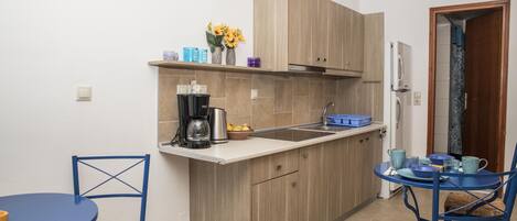 A compact kitchen with wooden cabinets, a sink, and a dining area with blue tables and chairs.