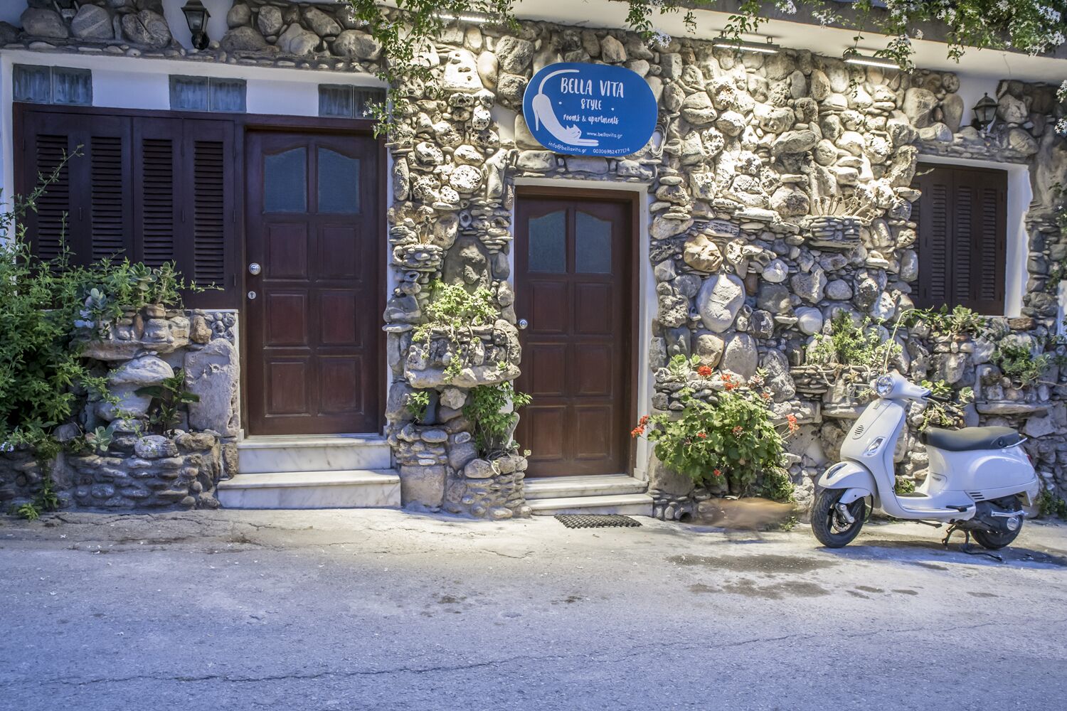 A stone building with two wooden doors and a blue sign above the right door.