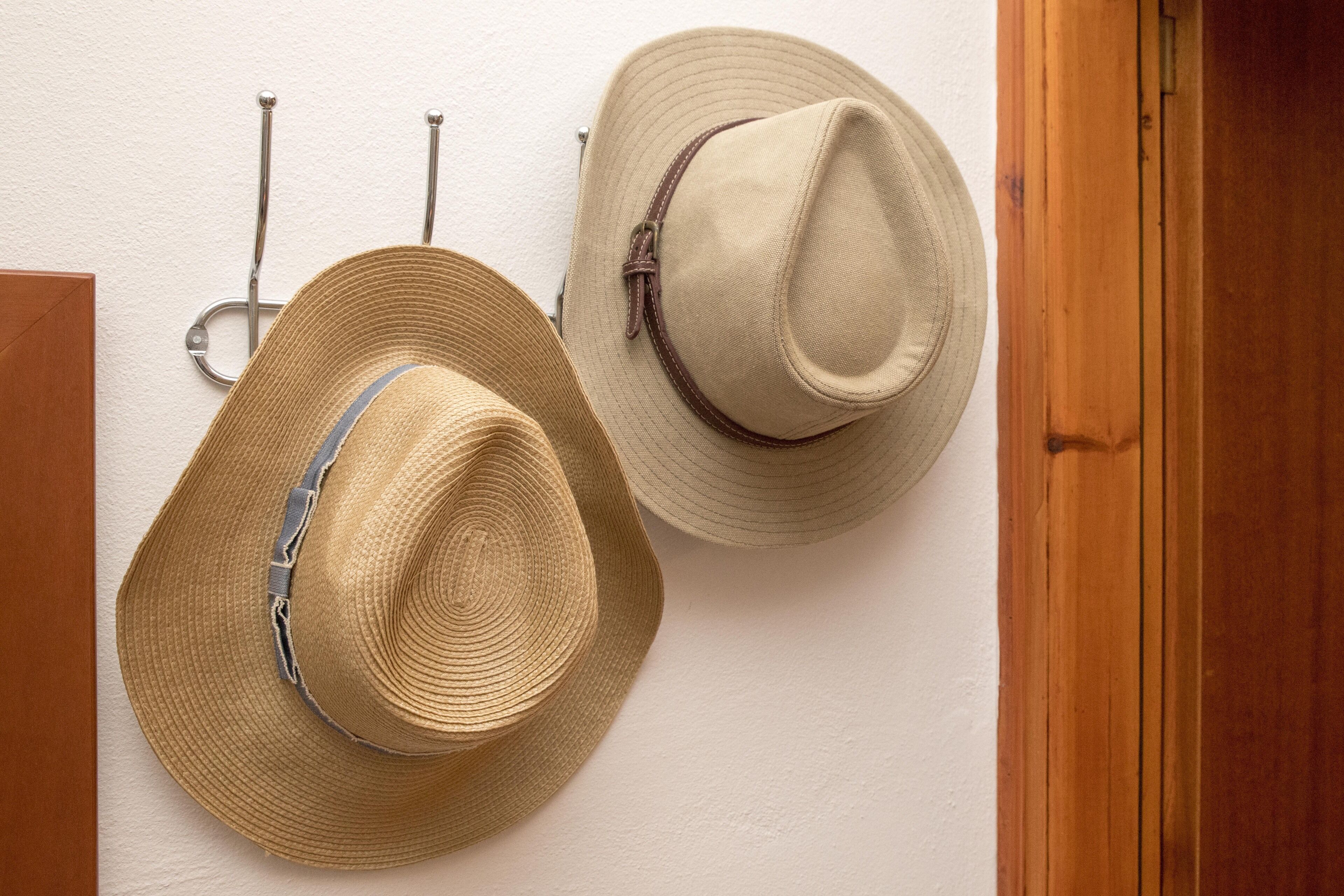 Two hats hanging on a wall.