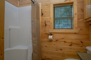 Enjoy a refreshing shower in this cabin-style bathroom with a shower area, window, and toilet.