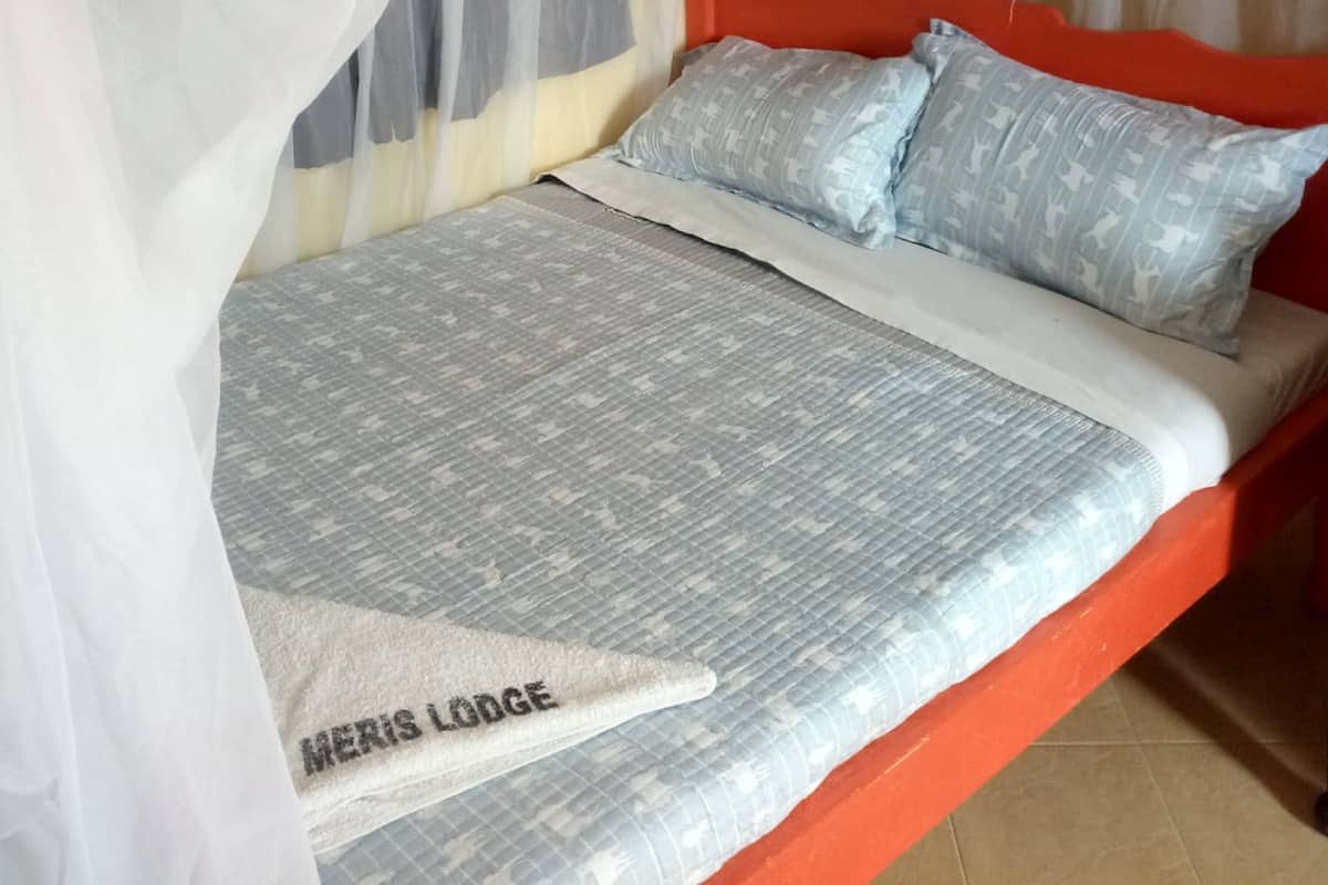 Una cama con dosel, ropa de cama gris estampada y almohadas con un diseño claro.