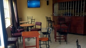 A dining area with multiple tables and chairs, a television mounted on the wall, and a sign indicating a smoking area. - Meris Lodge (Naivasha)
