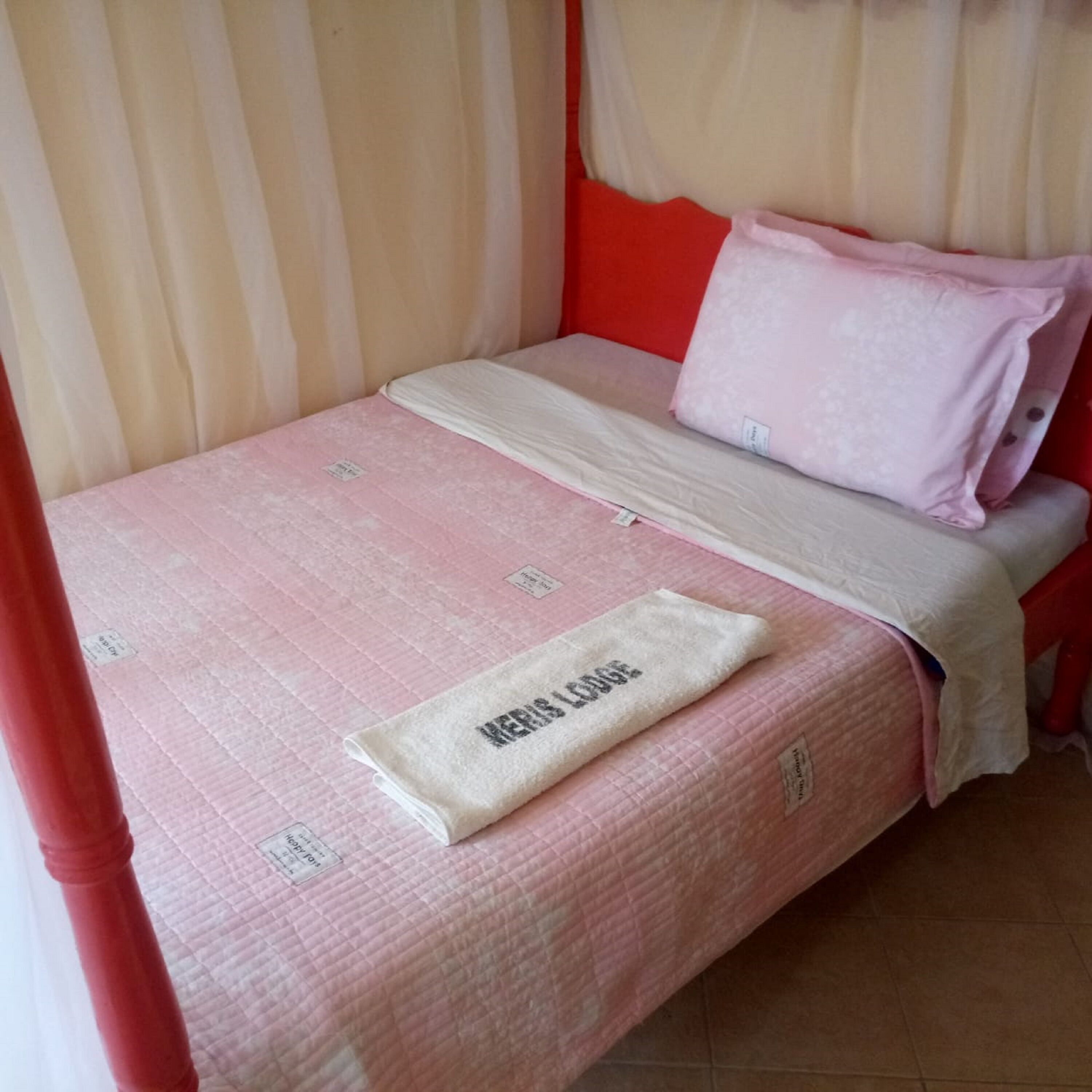 Un lit avec une couette rose, une couverture blanche et un oreiller.