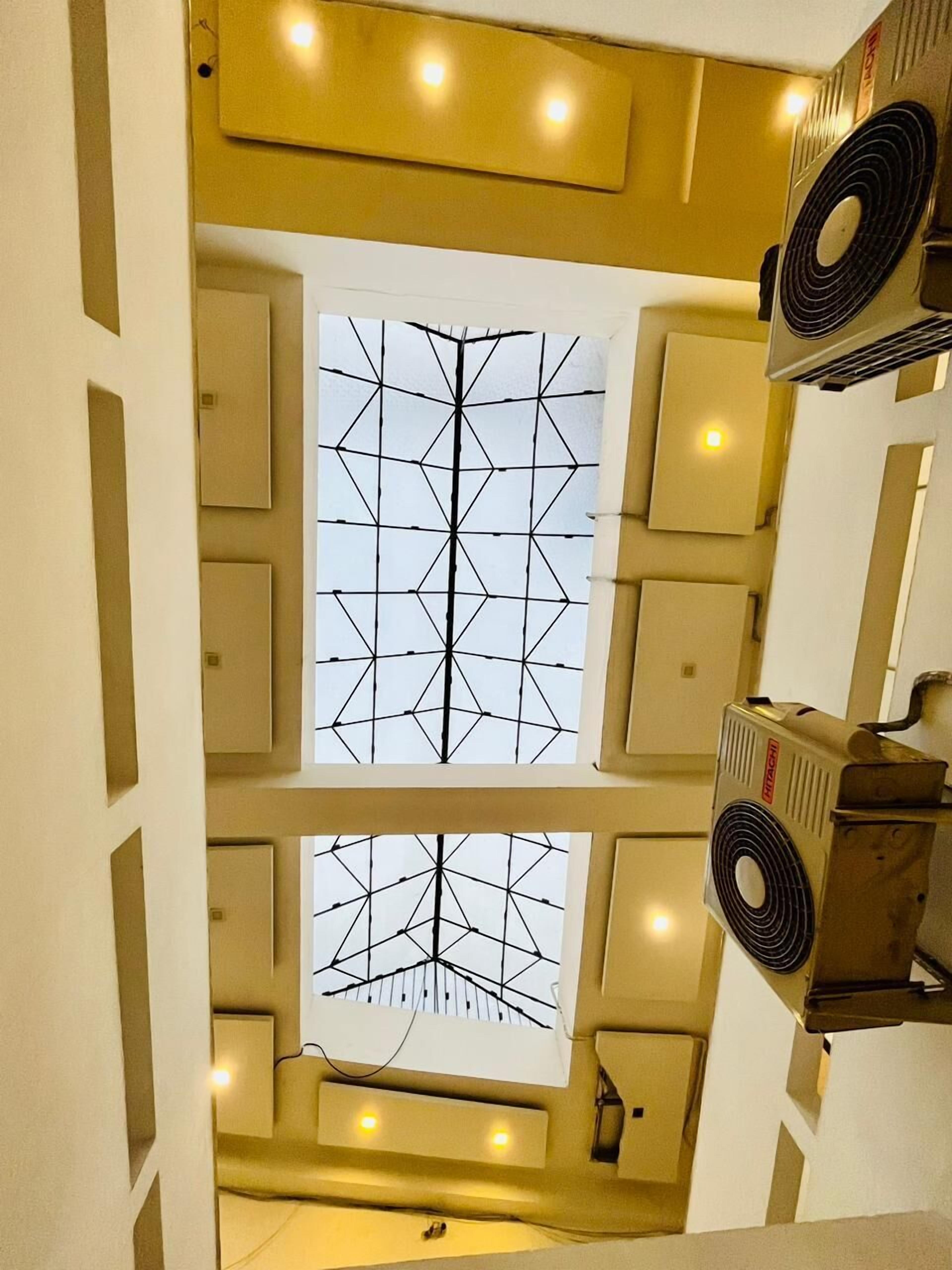 A multi-level interior with a central geometric window design, multiple air conditioning units, and recessed lighting.