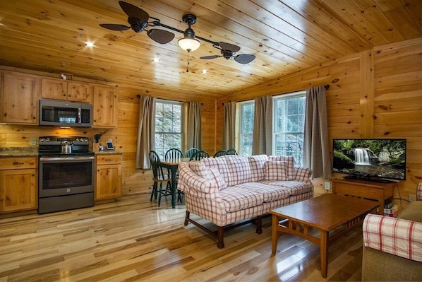 Interior de una cabaña de madera con cocina, comedor y sala de estar.