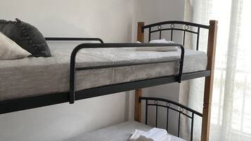A bunk bed room with a ceiling air conditioner, a window with sheer curtains, and a small basket on the lower bunk.