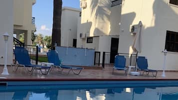 Una piscina al aire libre, sombrillas, sillones reclinables de piscina