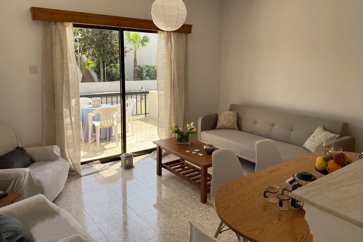 Ein modernes Wohnzimmer mit einer Couch, Sesseln, einem Couchtisch und einem Balkon mit Tisch und Stühlen.