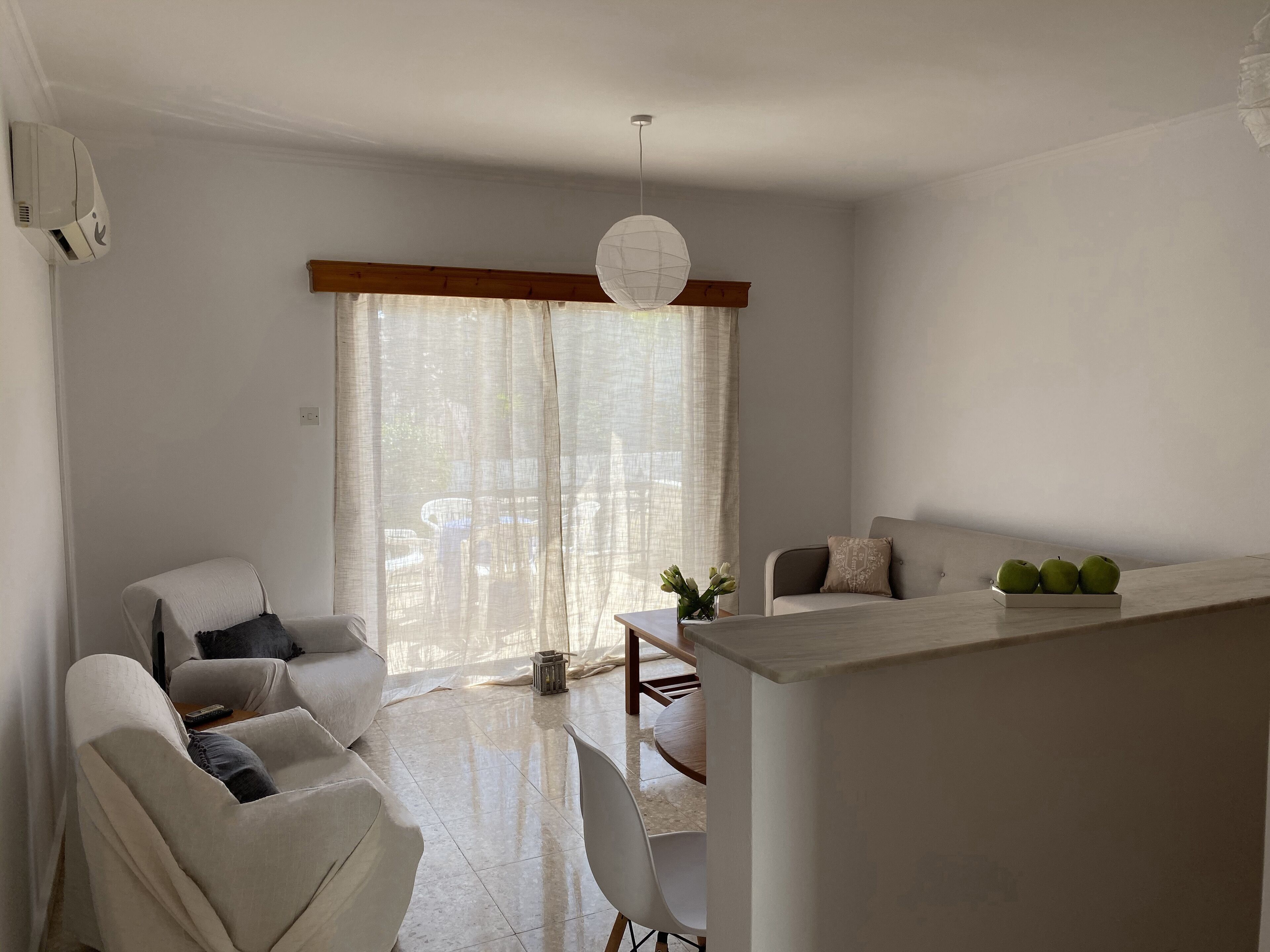A modern living room with a sofa, a dining table, and a kitchen area.