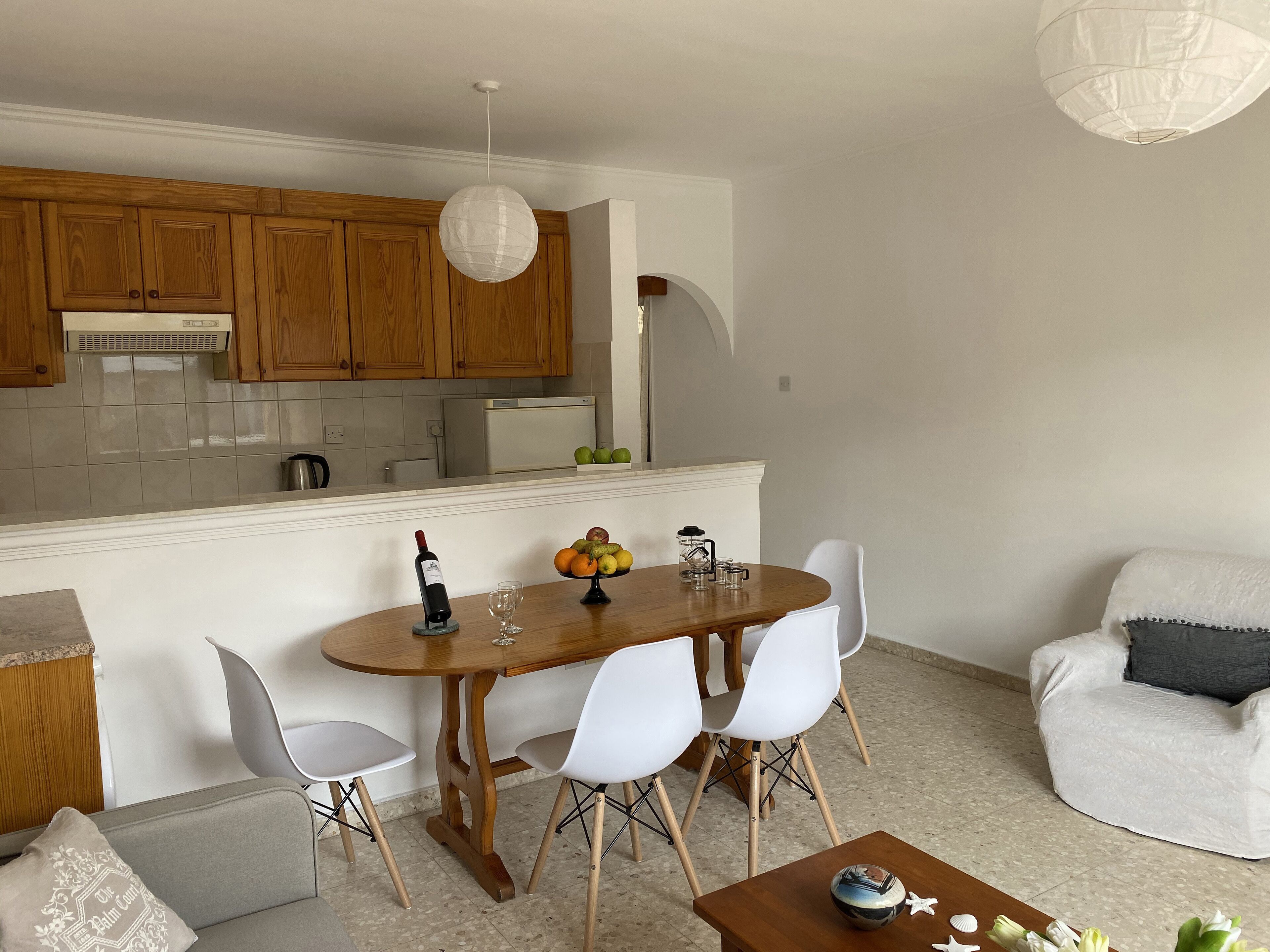 Una cocina moderna con armarios de madera, una mesa de comedor con sillas y un sofá blanco.